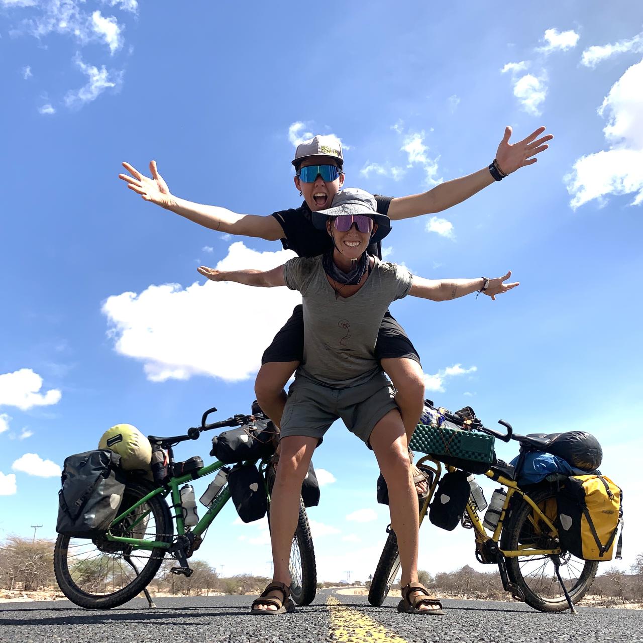 2 Frauen, 2 Räder auf einer Straße, im Hintergrund Himmel
